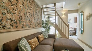 Een moderne woonkamer met een hoekbank, een trap en een groot abstract schilderij.