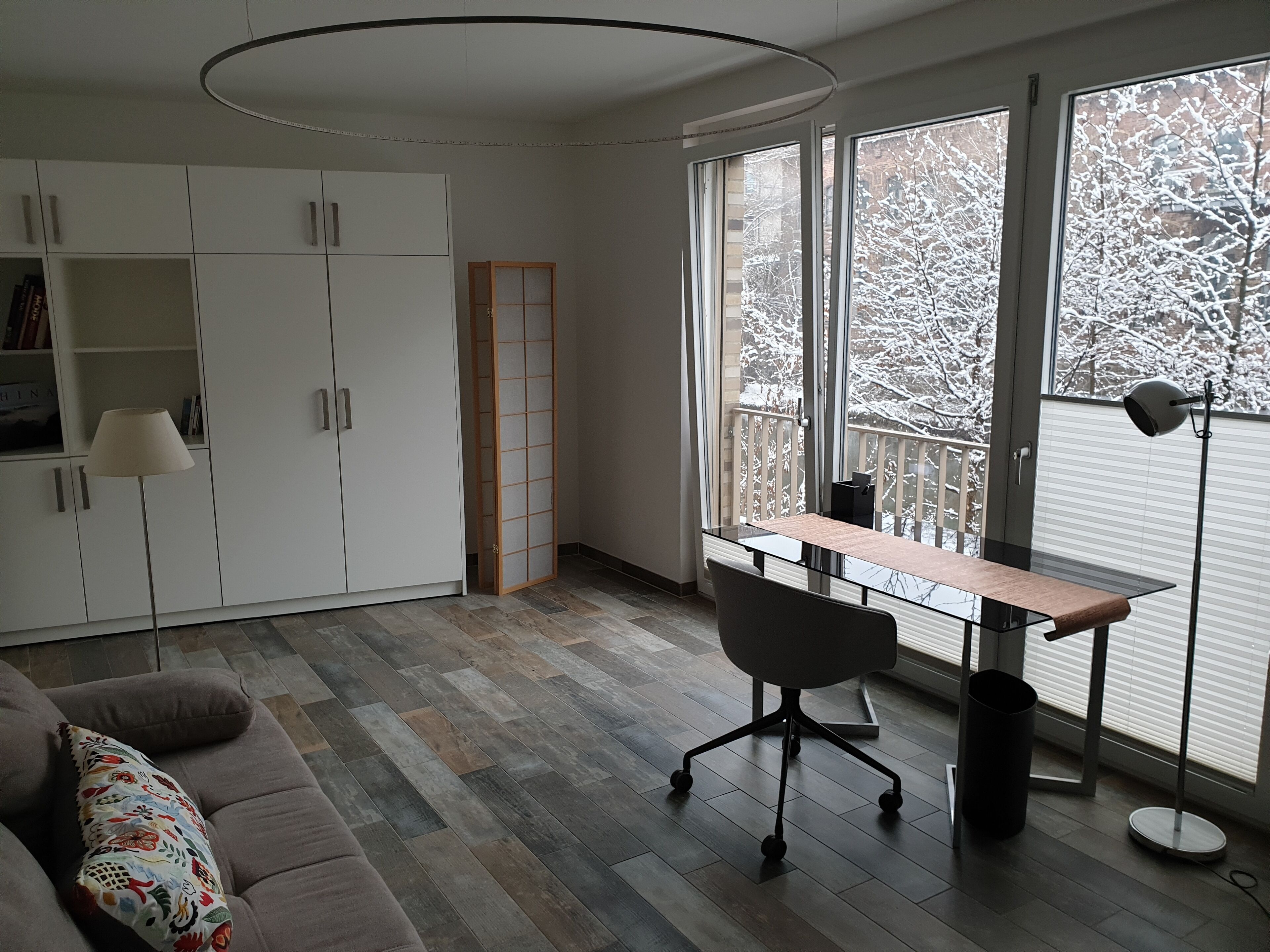 A modern living room with a sofa, a desk, and a bookshelf.