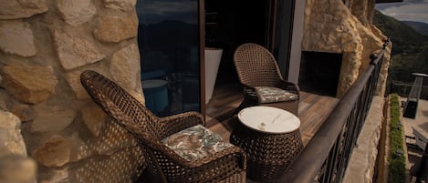 A balcony with wicker furniture, a round table, and a stone wall.