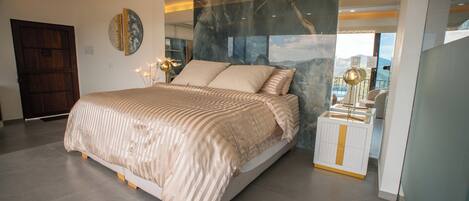 A modern bedroom with a large bed, a nightstand, and a view of the outdoors.
