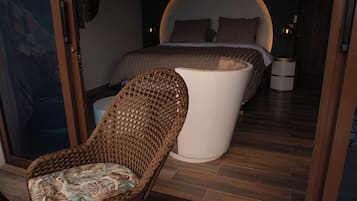 Una habitación con cama, una silla de mimbre y vistas al exterior.