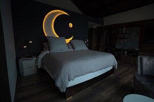 Un dormitorio moderno con una cama grande, una mesita de noche, una silla y un estante en la pared.