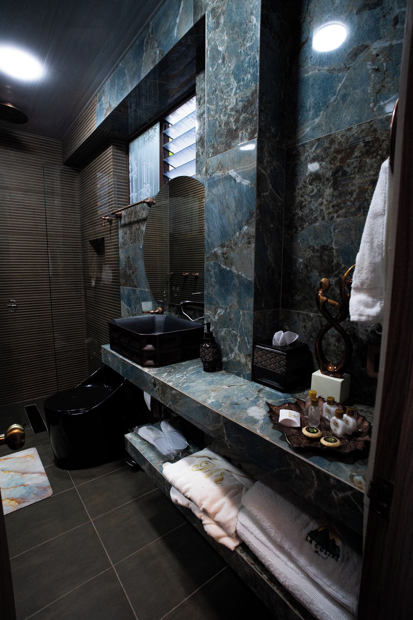 Un baño moderno con tocador de mármol, bañera negra y perchero.