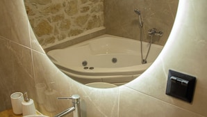 Un baño con pared de piedra, una bañera, un lavabo y una pequeña ventana.