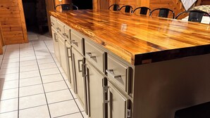 A kitchen with a wooden countertop, cabinets, and a tiled floor.