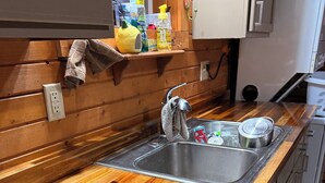 A kitchen with a wooden countertop, stainless steel sink, and wooden cabinets.