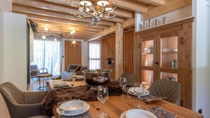 A dining area with a wooden table set for four, surrounded by upholstered chairs. A large metal bowl is placed in the center, and there are wine glasses and plates on the table. - Terrace, balcony, fireplace or stove, tv, 115m², Vars (Vars)
