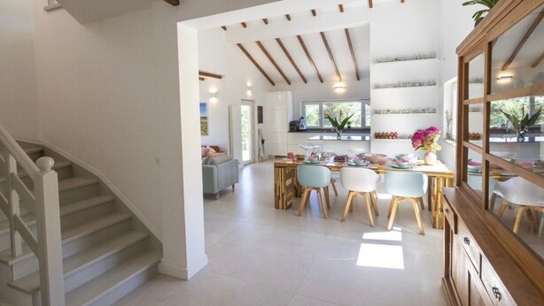 Un vaste espace de vie comprenant un escalier, un coin repas avec une table et des chaises, et une cuisine visible au fond.