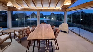 A spacious dining area with a wooden table and chairs, large windows offering a view of a swimming pool and surrounding landscape. - Villa with pool Porto Ottiolu (Porto Ottiolu)