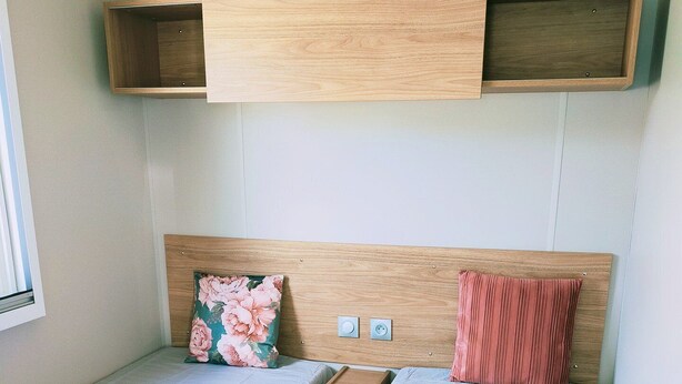 A room with two single beds, a wooden headboard, a small table, and a window. - Vakantiepark Klein Strand - Luxe Chalet 4p (Jabbeke)