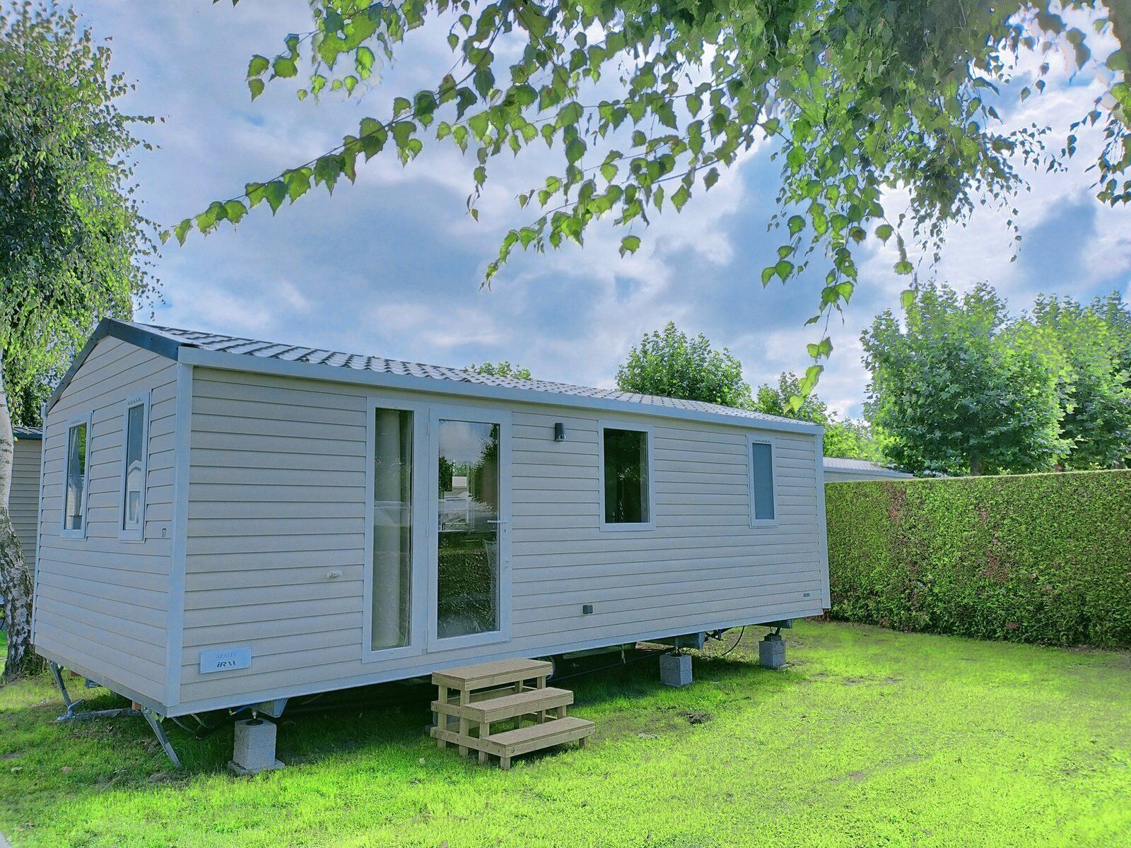 Une maison mobile de plain-pied avec une porte d’entrée, deux fenêtres et un petit porche.