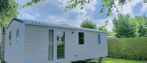 Une maison mobile de plain-pied avec une porte d’entrée, deux fenêtres et un petit porche.