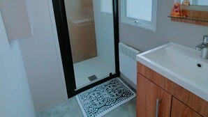 A bathroom with a shower, a sink, a mirror, and a window. - Vakantiepark Klein Strand - Luxe Chalet 4p (Jabbeke)