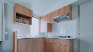 A kitchen with wooden cabinets, a gas stove, and a built-in oven. - Vakantiepark Klein Strand - Luxe Chalet 4p (Jabbeke)