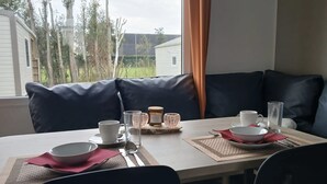 Un coin repas avec une table dressée pour deux personnes, offrant une vue sur l’extérieur.