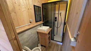 Un baño pequeño de madera con inodoro, lavabo y cabina de ducha de vidrio.