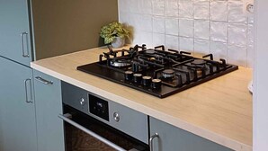 Una cocina moderna con gabinetes grises, una campana extractora de acero inoxidable, una estufa a gas y un salpicadero de azulejos.