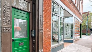 Uma porta verde com uma placa de 'Não Ficar', um prédio de tijolos e janelas grandes.