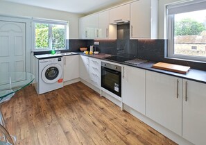 Een koelkast, een oven, kookgerei, borden en bestek