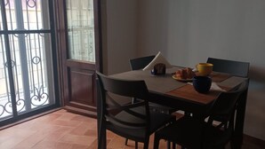 Un coin repas comprenant une table, des chaises, une tasse jaune, un bol bleu et une petite décoration en forme de maison.