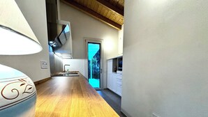 A modern kitchen with wooden flooring, a built-in oven, and a window with a view of greenery.