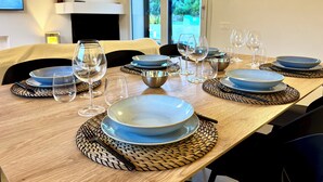A dining table set with blue plates, glasses, and a woven placemat.