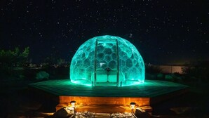 Une structure en forme de dôme, ornée d’un motif hexagonal, avec une base en bois et un ciel étoilé en arrière-plan.