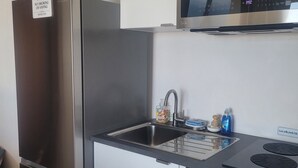 A compact kitchen with a stainless steel refrigerator, a microwave, a sink with a faucet, and a small countertop with a plant. - Ocean Sunsets 1 bd Guesthouse
Forever ocean views, short stroll to the sand  (Malibu)