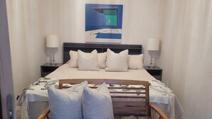 A neatly arranged bedroom with a bed, two bedside tables, a chair, and a wall-mounted artwork. - Ocean Sunsets 1 bd Guesthouse
Forever ocean views, short stroll to the sand  (Malibu)