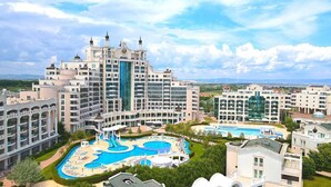 Un grand hôtel doté de plusieurs piscines, d’un toboggan aquatique central et offrant une vue sur le paysage environnant.
