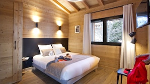 Un dormitorio de cabaña de madera con cama, lámparas de noche, ventana y televisor.