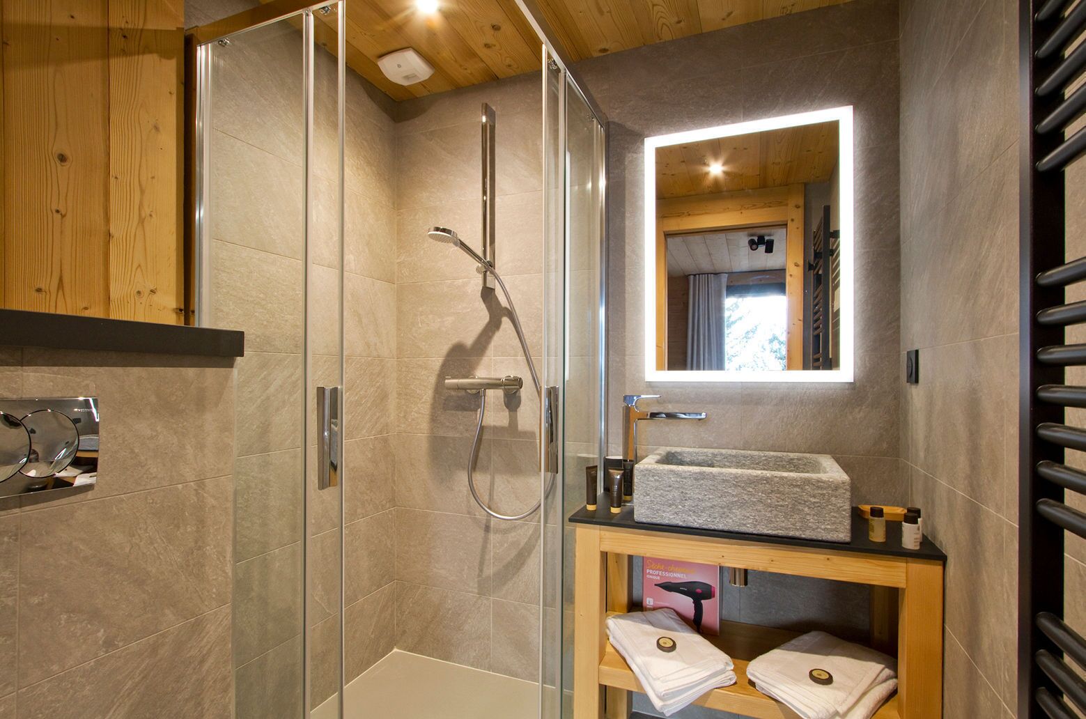 Une salle de bain moderne dotée d’une cabine de douche en verre, d’un lavabo intégré et d’un meuble-lavabo avec des serviettes.