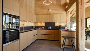 Una cocina moderna con armarios de madera, horno empotrado y una zona de bar con taburetes.