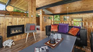 Een blokhutinterieur met een open haard, zithoek en een bijzettafeltje.
