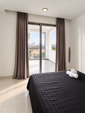A hotel room with a bed, curtains, a view of the city, and a balcony. - Uhouse - MELIA Thao Dien Hotel & Apartment (Ho Chi Minh City)