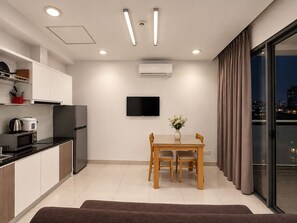 Una cocina moderna con zona de comedor, televisor de pantalla plana y vistas a la ciudad de noche.