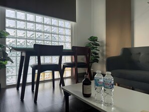 A modern room with a large window, two chairs, a table, and a sofa. There are two bottles on the table. - Uhouse - MELIA Thao Dien Hotel & Apartment (Ho Chi Minh City)
