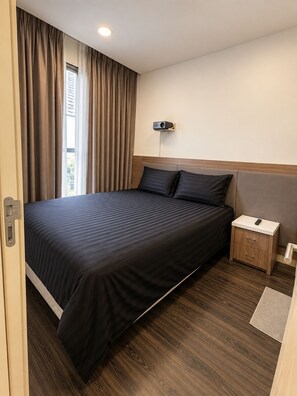 Une chambre d’hôtel avec un grand lit, une table de chevet avec une télécommande et un projecteur fixé au mur.