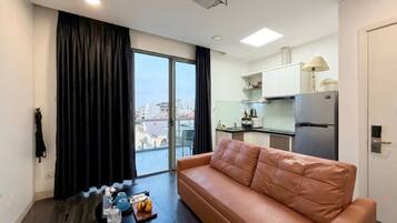 Una sala de estar moderna con un sofá, una mesa de centro y vistas de la ciudad a través de amplias ventanas.