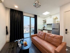 Uma sala de estar moderna com um sofá, uma mesa de centro e vista para a cidade através de amplas janelas.