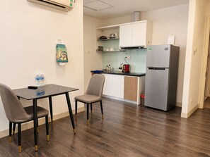 Una kitchenette compacta con refrigerador, lavamanos y encimera. Cuenta con un comedor con mesa y sillas.