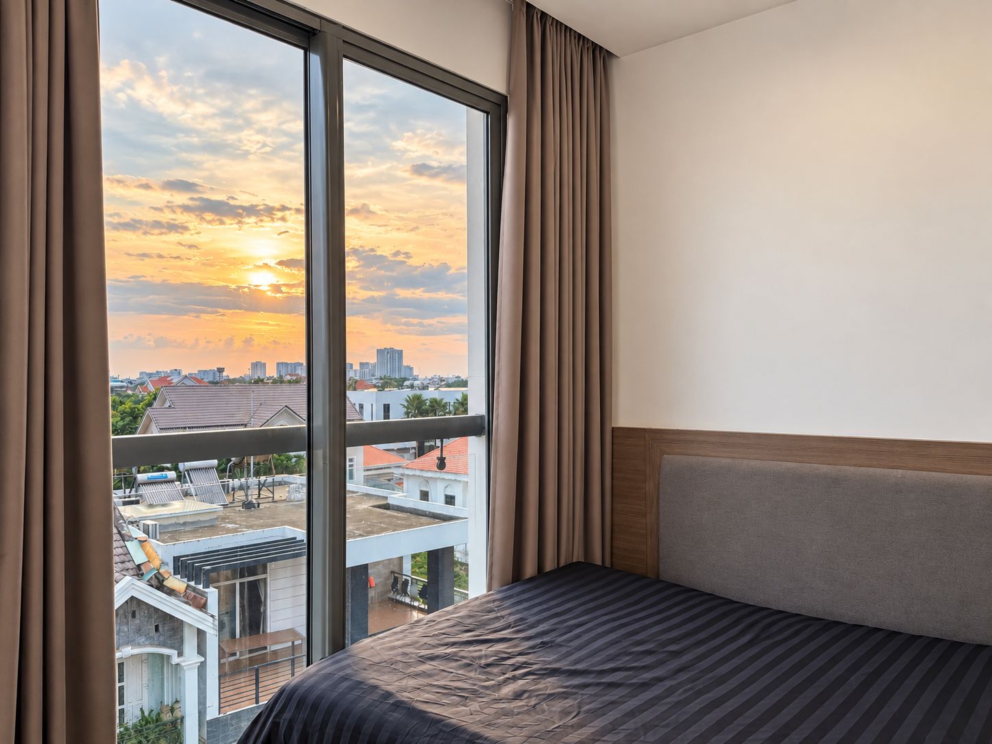 Une chambre d’hôtel avec une grande fenêtre, un lit et une vue sur le paysage urbain.