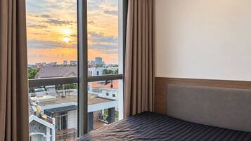 Une chambre d’hôtel avec une grande fenêtre, un lit et une vue sur le paysage urbain.