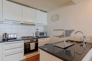 Eine Küche mit weißen Schränken, einem Gasherd, einer Mikrowelle, einem Toaster und einem Spülbecken mit Seifenspender.