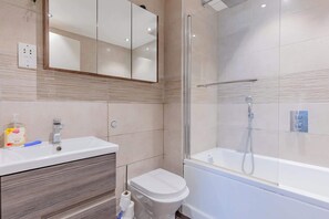 Een moderne badkamer met een wastafel, toilet en douche.