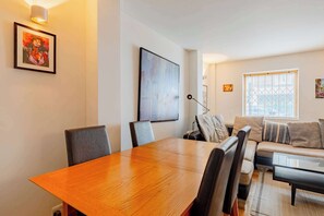 Ein modernes Wohnzimmer mit einem Holzesstisch, einer Couch und einem großen Fenster mit Jalousien.