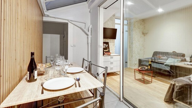 Un espace repas moderne avec une table en verre, des chaises et une bouteille de vin.