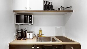 Une cuisine compacte équipée d’un four à micro-ondes, d’un grille-pain, d’une machine à café et d’un évier.