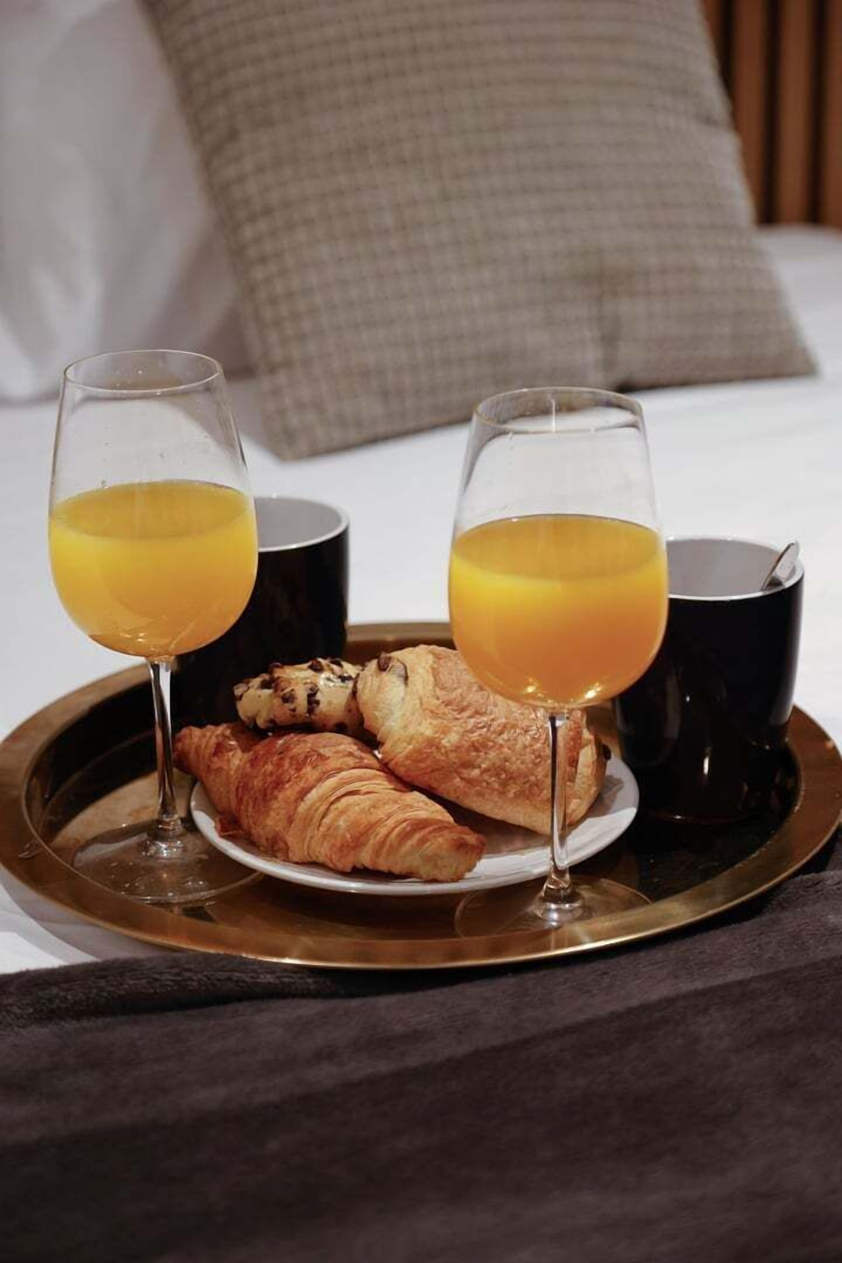Un plateau avec des croissants et des verres de jus d’orange, évoquant un petit-déjeuner.