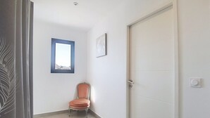 A hallway with a closed door, a window, and a chair. - Villa cami del paradis (Corneilla-del-Vercol)